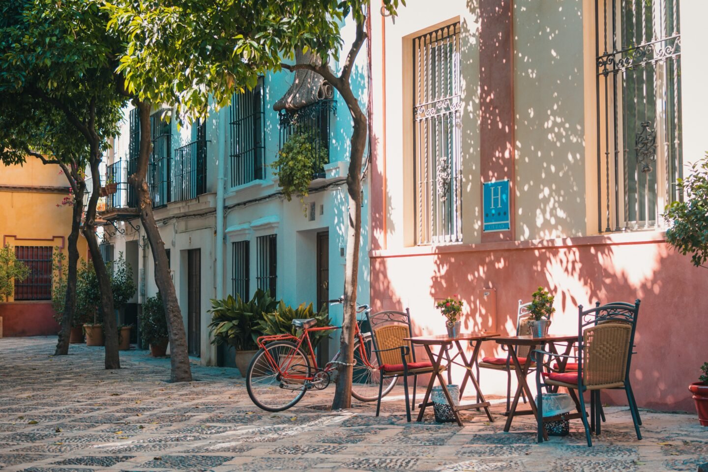 A red bicycle beside a cafe table on a street in Seville